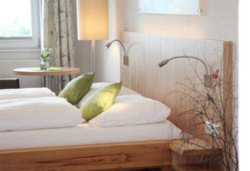 a bed with white pillows and a table with a lamp at AKZENT Hotel Altes Casino in Fulda