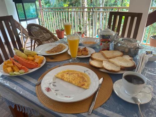 a table with plates of breakfast foods and a cup of coffee at Cecilia Unawatuna Rooms in Unawatuna
