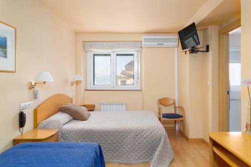 a hotel room with a bed and a television at Hotel Villa de Ayerbe in Ayerbe