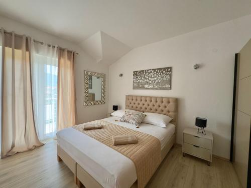 une chambre avec un grand lit et une grande fenêtre dans l'établissement Apartments Dalmatino, à Kaštela