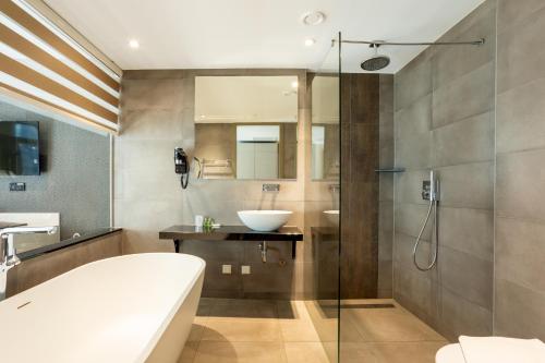 a bathroom with a tub and a sink and a shower at Dream Hotel Amsterdam in Amsterdam