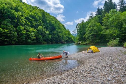 two people in a canoe on a river with a tent at Deer Land Photo Apartment in Kočevska Reka
