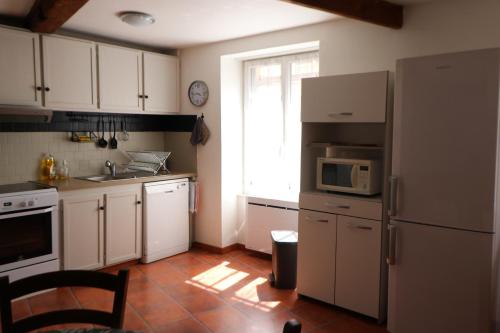 La cuisine est équipée d'un réfrigérateur blanc et d'un four micro-ondes. dans l'établissement Chambres et salles d'eau privées dans maison à partager Centre Clermont-Ferrand, à Clermont-Ferrand