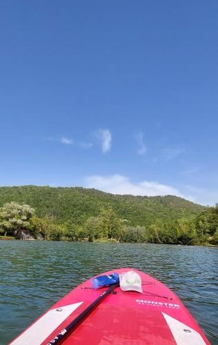 a red boat in the water on a lake at Deer Land Photo Apartment in Kočevska Reka