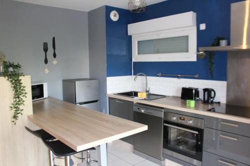 une cuisine avec des murs bleus et un comptoir en bois dans l'établissement La Revalia Chessy, à Chessy