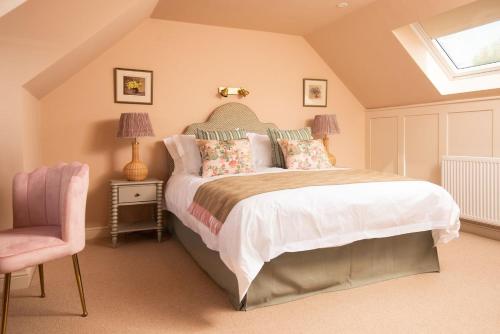 een slaapkamer met een bed en een roze stoel bij Wall Cottage in Coldstream