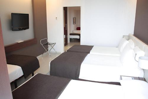 a hotel room with two beds and a flat screen tv at Hotel Diagonal Plaza in Zaragoza