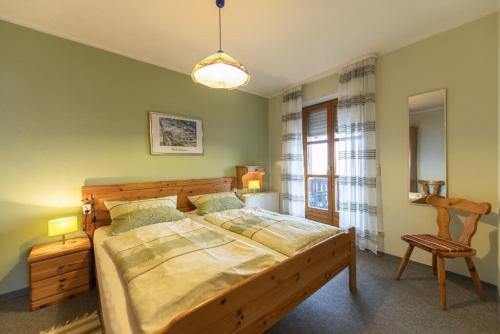 a bedroom with a large wooden bed and a chair at Pension Ferienwohnungen Frey in Tännesberg
