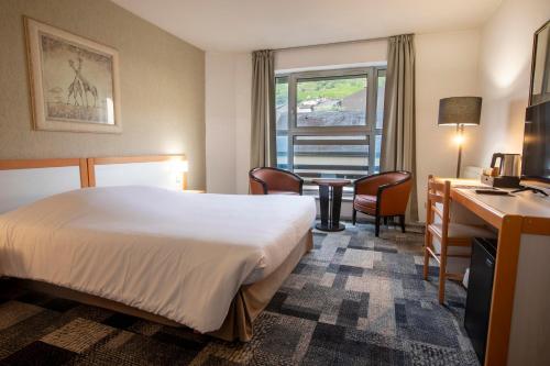 a hotel room with a bed and a table and chairs at Hôtel Paradis in Lourdes