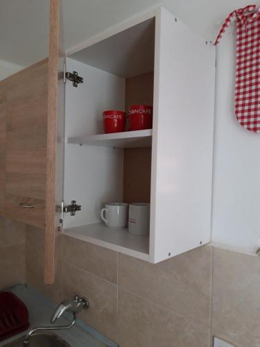 a cupboard in a kitchen with red bowls in it at Apartment for 2 in the house in Sutomore