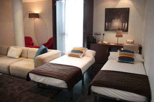 a hotel room with two beds and a couch at Hotel Diagonal Plaza in Zaragoza