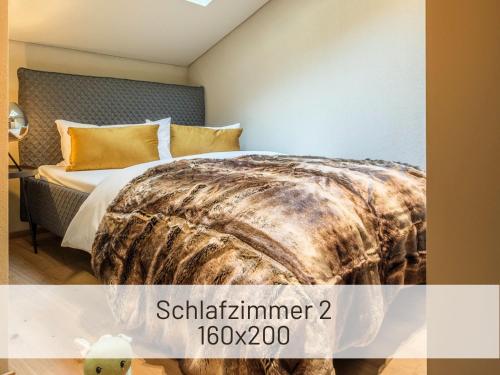 a bedroom with a bed with a blanket on it at Hoimat Pfronten - Luxusappartements mit Sauna und Bergblick in Pfronten