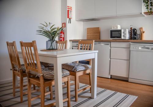 a kitchen with a white table and chairs in a kitchen at House Pachamama in Olhão