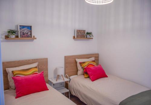 two beds in a room with pink and yellow pillows at House Pachamama in Olhão