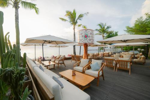a restaurant with tables and chairs and umbrellas at Griya Santrian a Beach Resort And Spa in Sanur