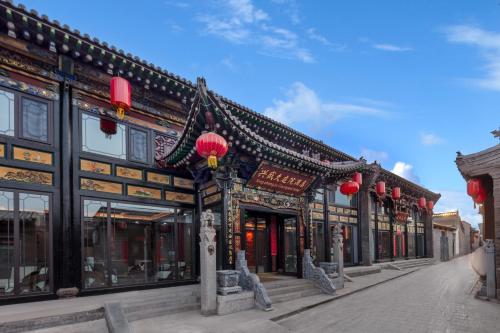 a building with red lanterns on a street at Xingshengjiu Courtyard Hotel Pingyao in Pingyao