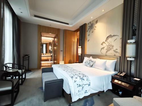 a bedroom with a large white bed and a chair at Wanda Realm Liuzhou in Liuzhou