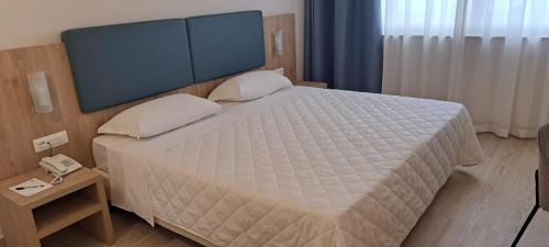 a bedroom with a large white bed with a telephone at San Paolo Palace Hotel in Palermo