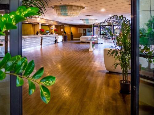 an empty lobby with plants in the foreground at San Paolo Palace Hotel in Palermo