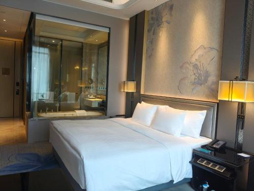 a bedroom with a large white bed and a bathroom at Wanda Realm Liuzhou in Liuzhou