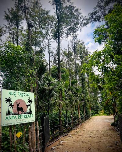 a sign on a fence next to a dirt road with trees at Anya Retreats Nature Homestay in Kushālnagar