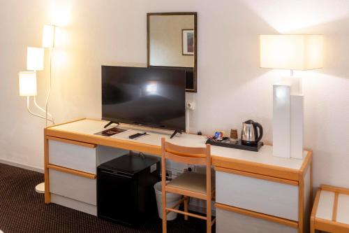 a hotel room with a desk with a television at Hôtel Paradis in Lourdes