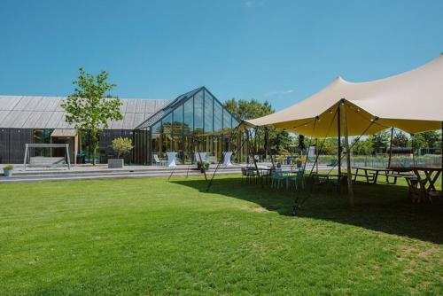 a park with tables and umbrellas in front of a building at Vakantiehuis Zuid-Holland nabij zandstrand VP073 in Ouddorp