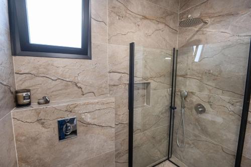 a shower with a glass door in a bathroom at רוי סוויטות בוטיק - סוויטה עם בריכה פרטית וסוויטה עם ג'קוזי פרטי in Yavneʼel