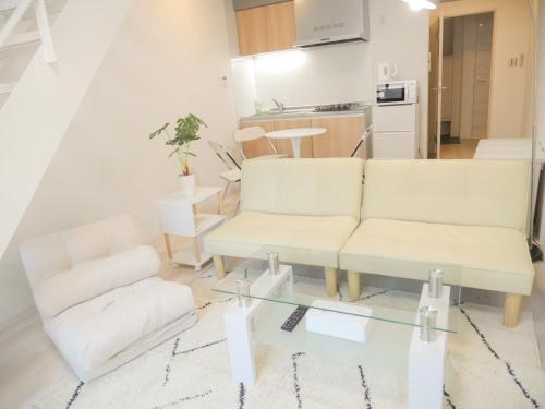 a living room with two white couches and a glass table at 9Stay文京大塚 in Tokyo