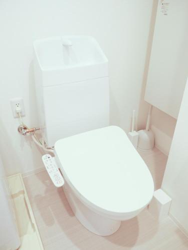 a white toilet in a bathroom with a remote control at 9Stay文京大塚 in Tokyo