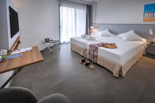 a hotel room with two beds and a desk at GHT S'Agaró Mar Hotel in Sant Feliu de Guixols