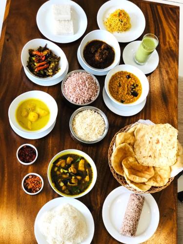 a wooden table with plates of different types of food at Royal Lion Hotel - Kandy Road, Galagadara in Galagedara