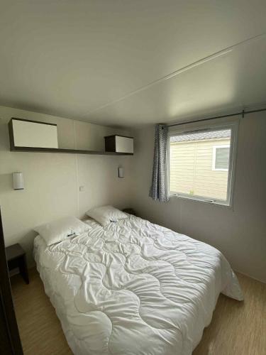 a white bed in a bedroom with a window at Mobile home à Mimizan in Mimizan