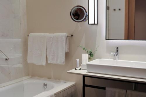 a white bathroom with a tub and a sink and a bath tub at Hospes Palau de La Mar, Valencia, a Member of Design Hotels in Valencia