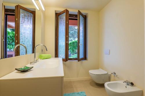 a bathroom with a sink and a toilet and windows at Casa Bella Vista in Laveno