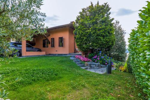 a house with a green yard with flowers and trees at Casa Bella Vista in Laveno