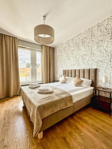 a bedroom with a large bed and a large window at Uniwersytecki by Rentoom in Toruń