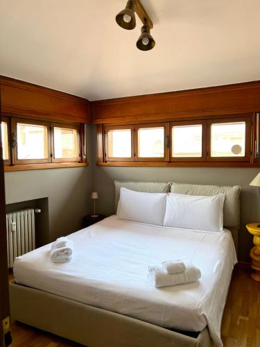 een slaapkamer met een groot wit bed en ramen bij La Mansardina in Parma