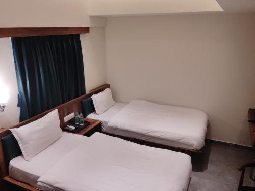 a hotel room with two beds and a window at Hotel Aasare Inn in Bengaluru