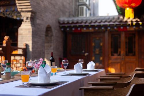 a row of tables with white napkins and wine glasses at Xingshengjiu Courtyard Hotel Pingyao in Pingyao