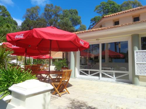 a patio with a red umbrella and a table and chairs at Green Park Departamentos Exclusivos in Punta del Este