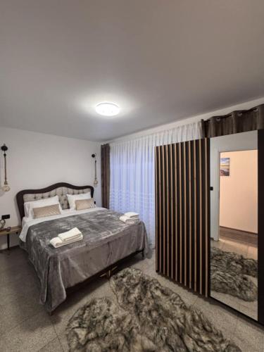 a bedroom with a large bed and a large window at Apartman Booem in Bihać