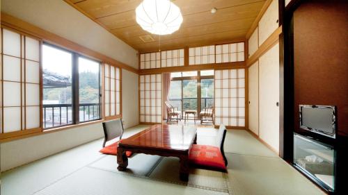 a dining room with a table and chairs and windows at Ayameya Ryokan in Nakanojo