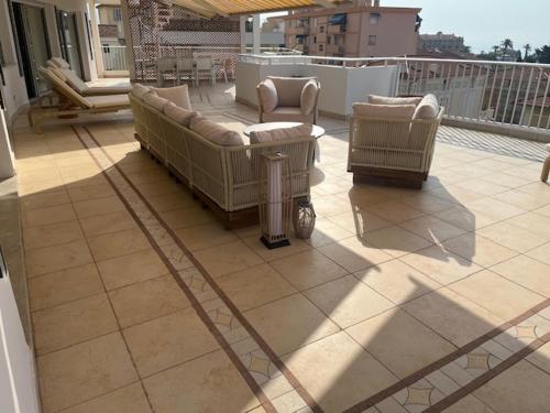 a patio with couches and chairs on a balcony at Résidence Carlton - Rénovée avec Piscine in Beaulieu-sur-Mer