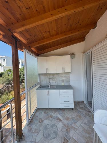a kitchen with white cabinets and a wooden ceiling at CAUSHI Apartments Ksamil in Ksamil
