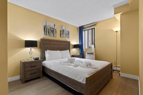 a bedroom with a large bed with white sheets at Modern 2 bedroom next to Stampede, 17th w Parking in Calgary