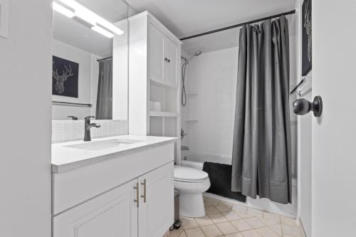 a white bathroom with a toilet and a sink at Modern 2 bedroom next to Stampede, 17th w Parking in Calgary