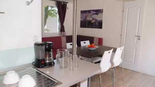 a kitchen with a table with a blender and white chairs at Appartement 4 étoiles - Parc aquatique - ccaa0ai in Bormes-les-Mimosas