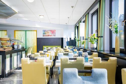 a dining room with tables and yellow chairs at HOTEL Am Spichernplatz in Düsseldorf