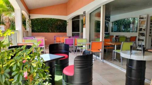 a restaurant with tables and chairs and colorful chairs at Appartement 4 étoiles - Parc aquatique - ccaa0ai in Bormes-les-Mimosas